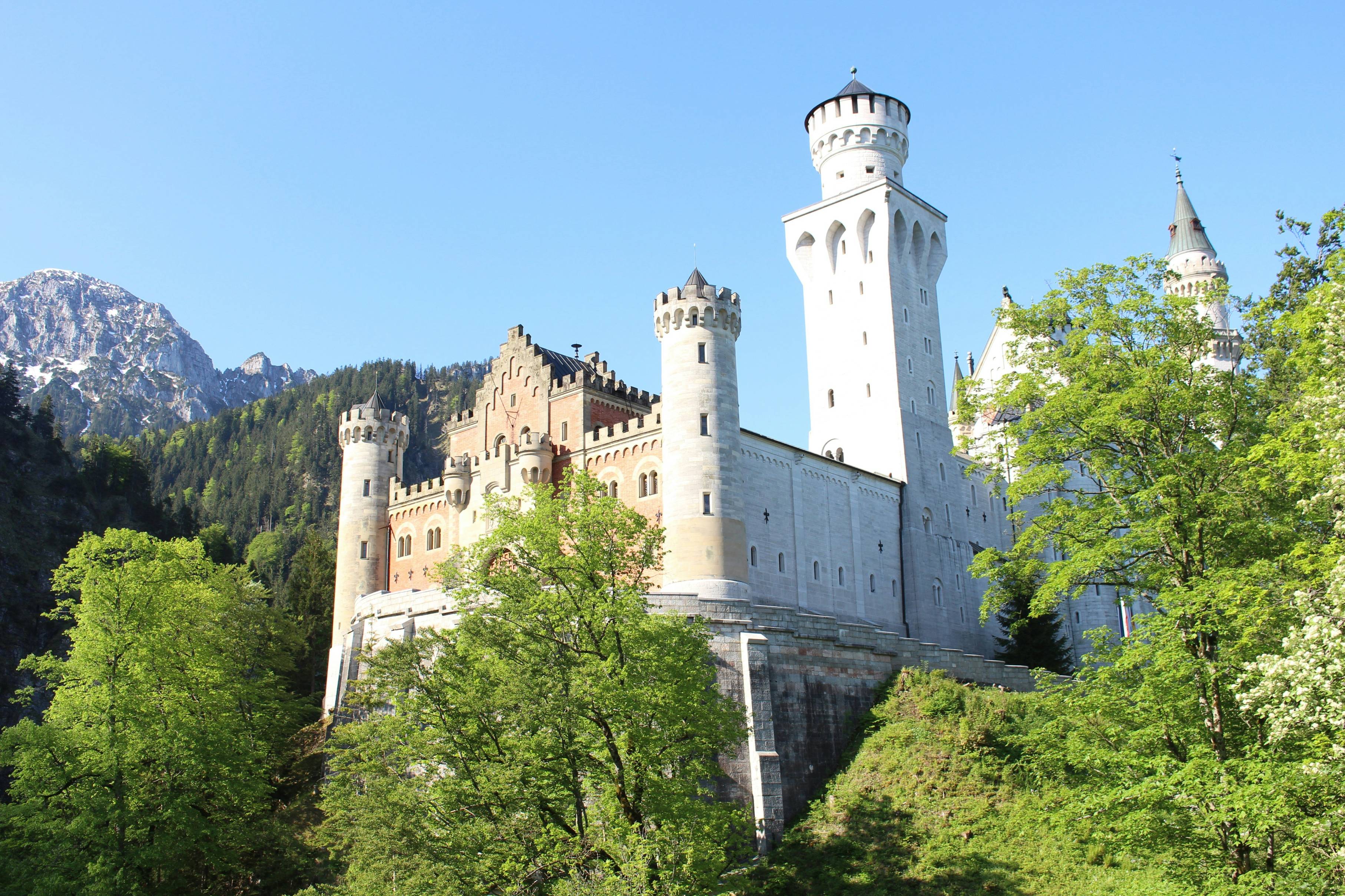 white concrete castle on top of green mountain