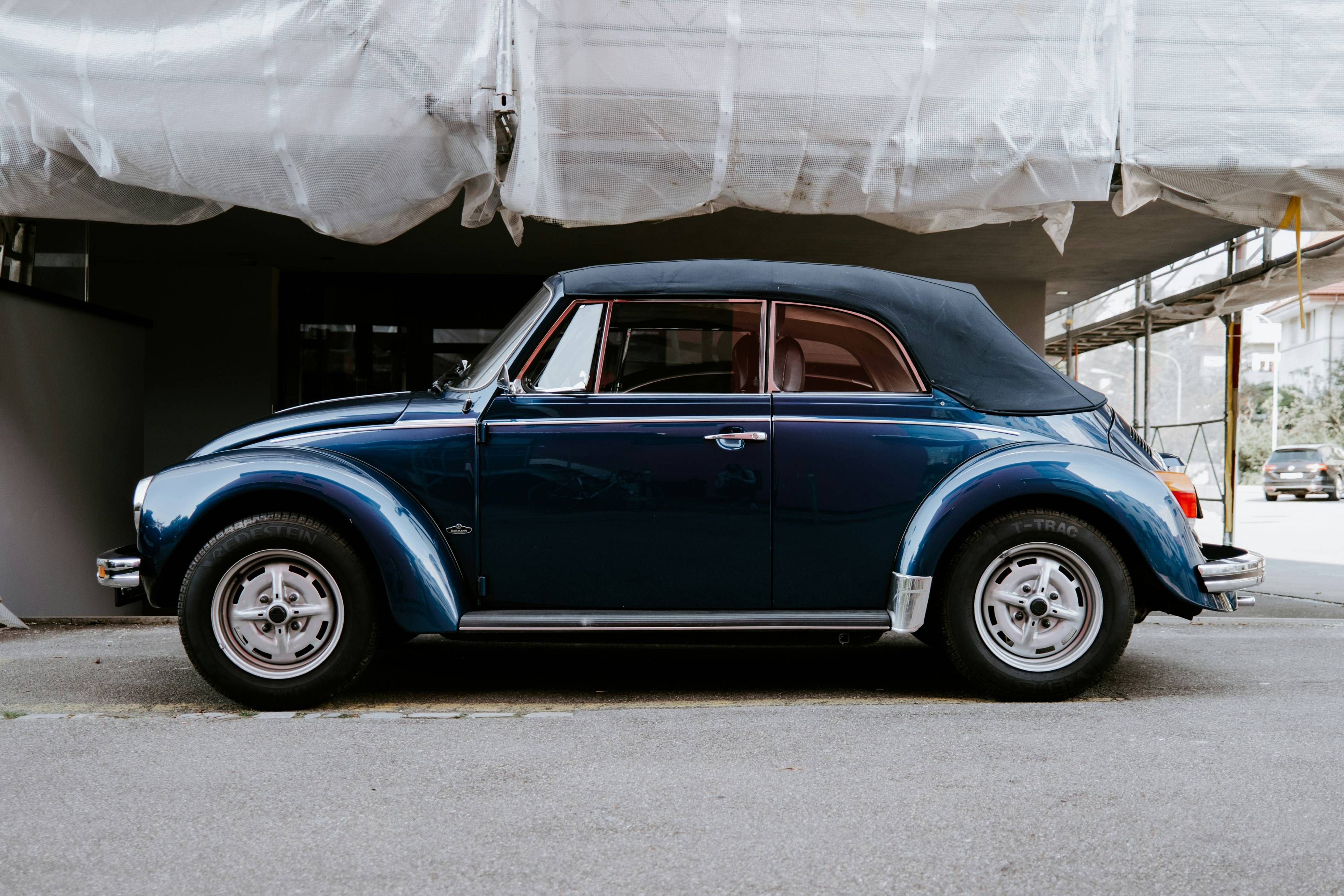 blue classic car parked beside white wall